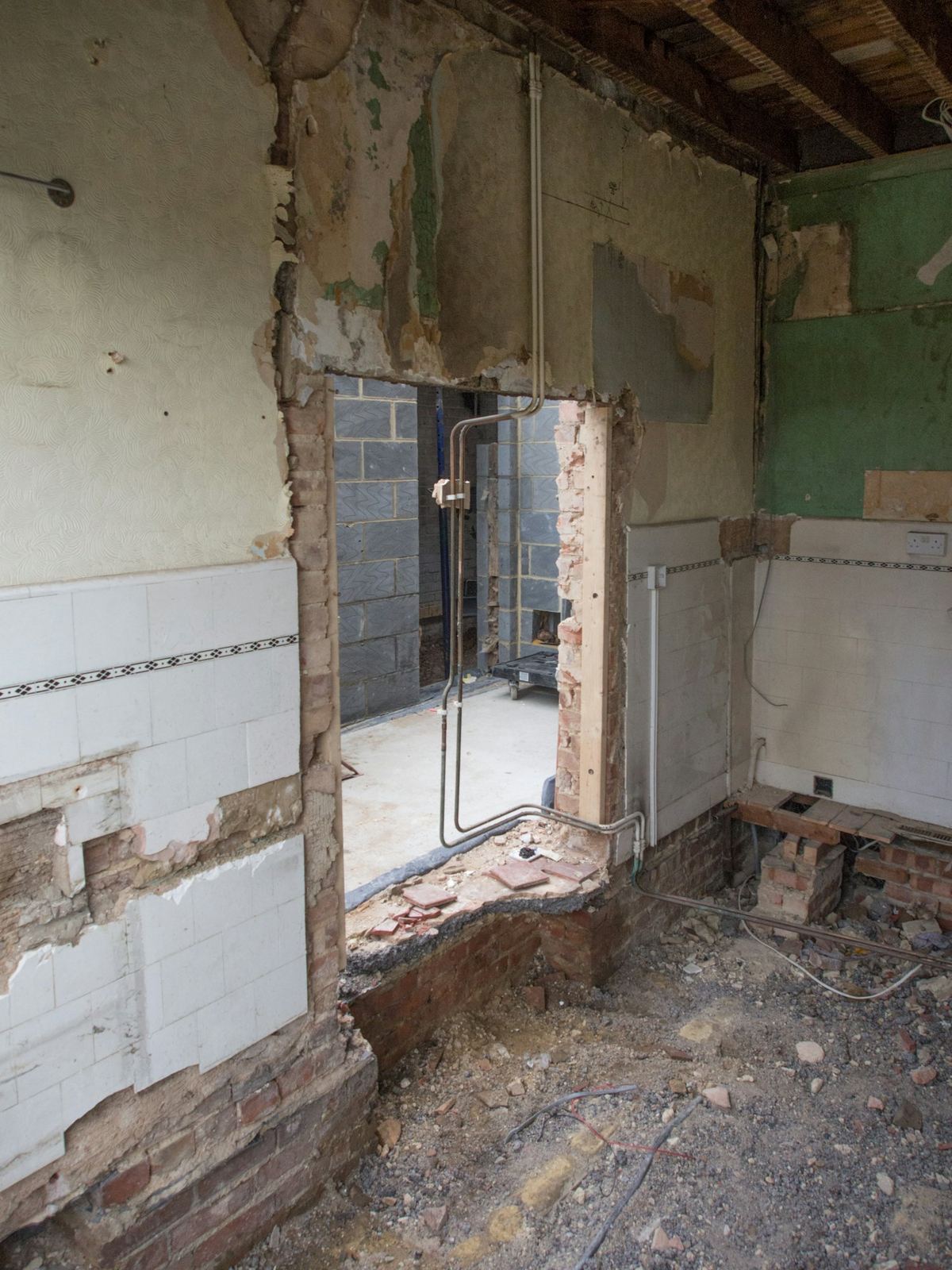 A bathroom stripped back, pipework exposed, mid-renovation